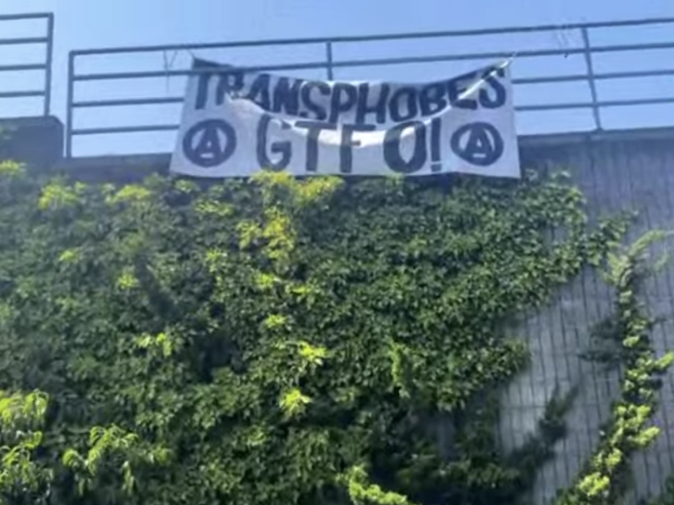 Banner reading, "TRANSPHOBES GTFO!" surrounded by circle A's.
